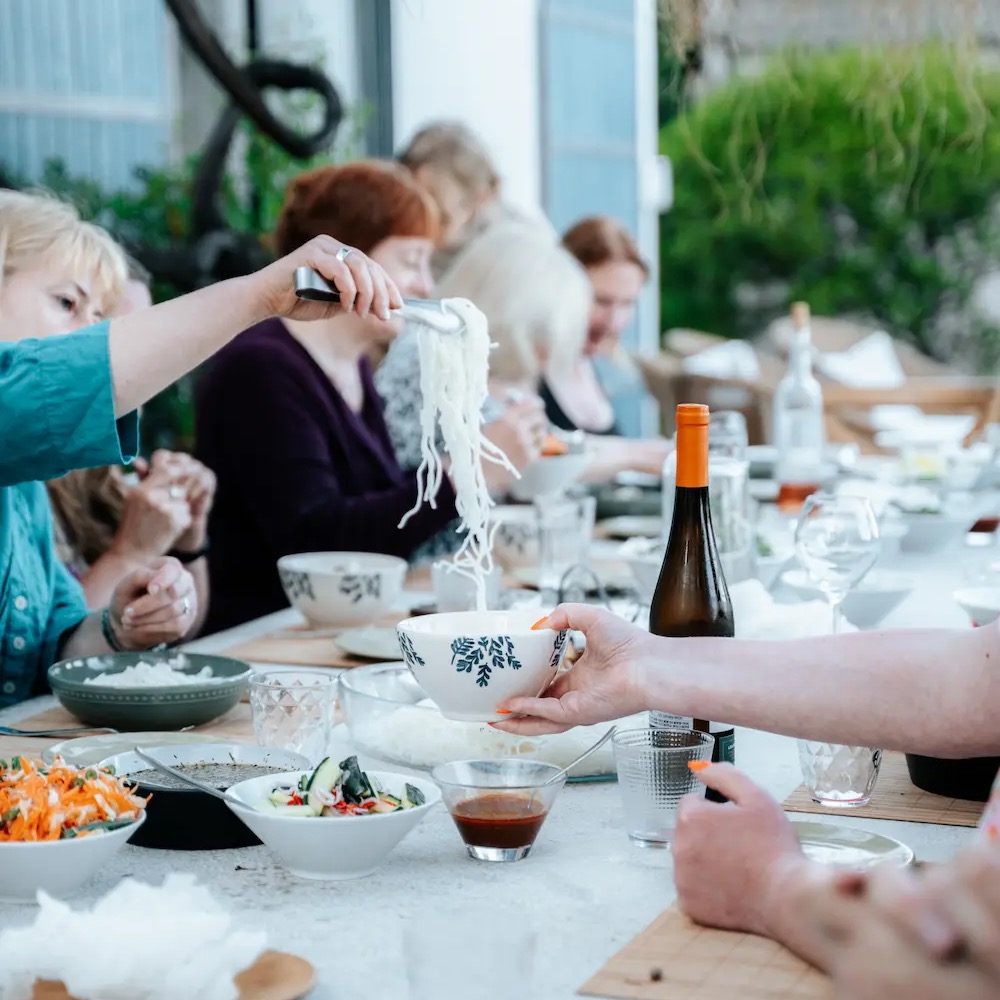 Retreat guests sharing a communal outdoor dinner with local wine at the France wellness retreat