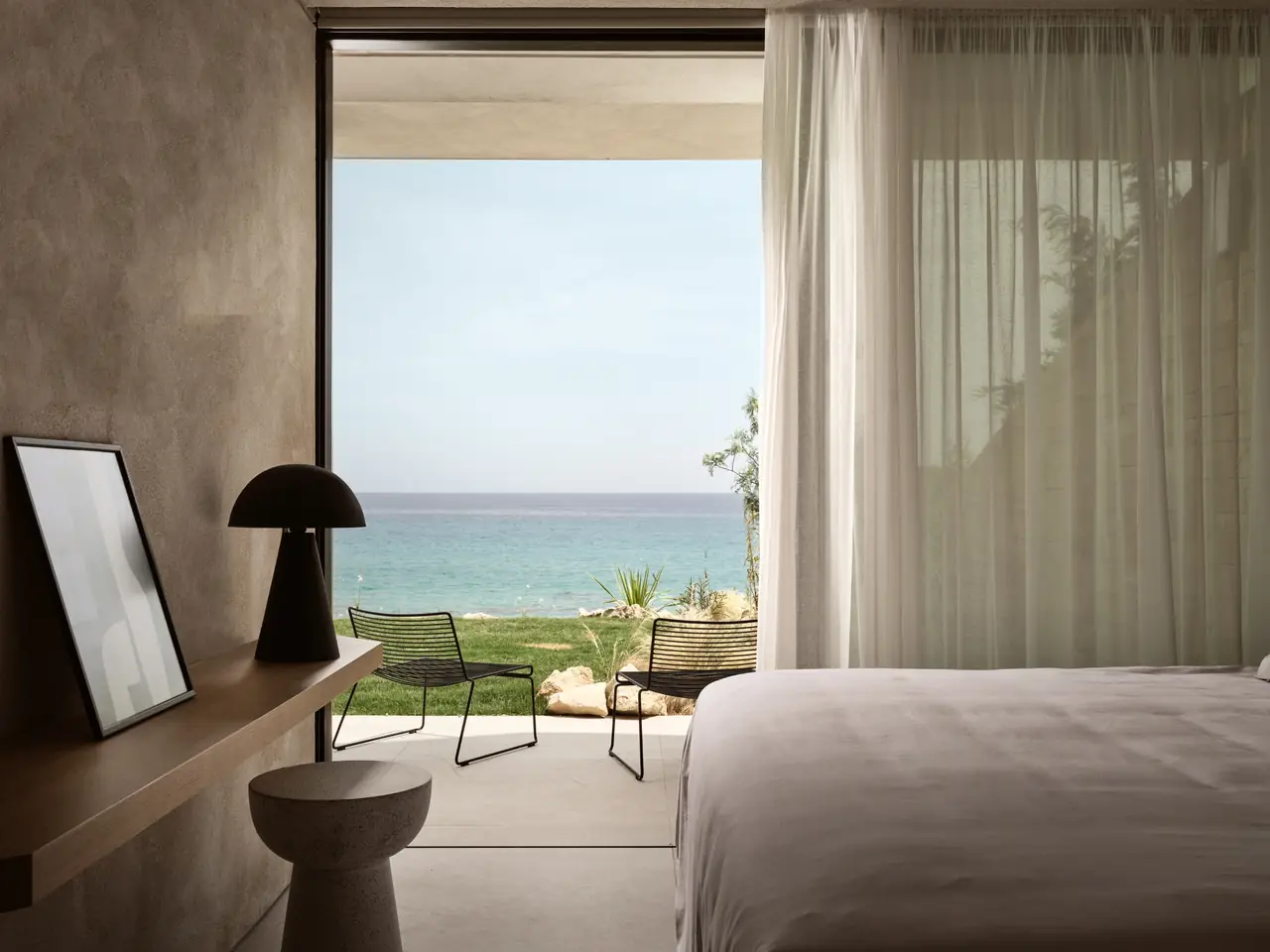 A calm bedroom opening onto the garden with the sea beyond