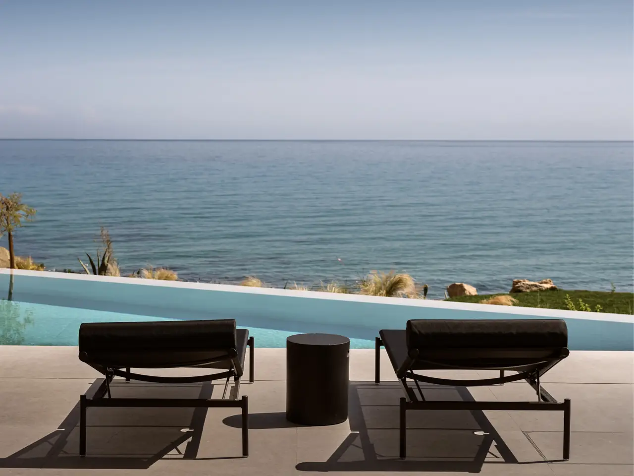 Sun loungers beside the infinity pool, looking out to sea