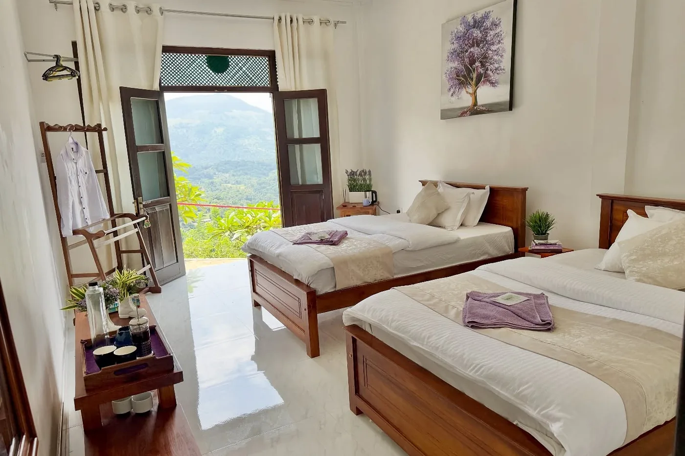 Twin room at Welikande with two wooden beds and doors onto the mountain view