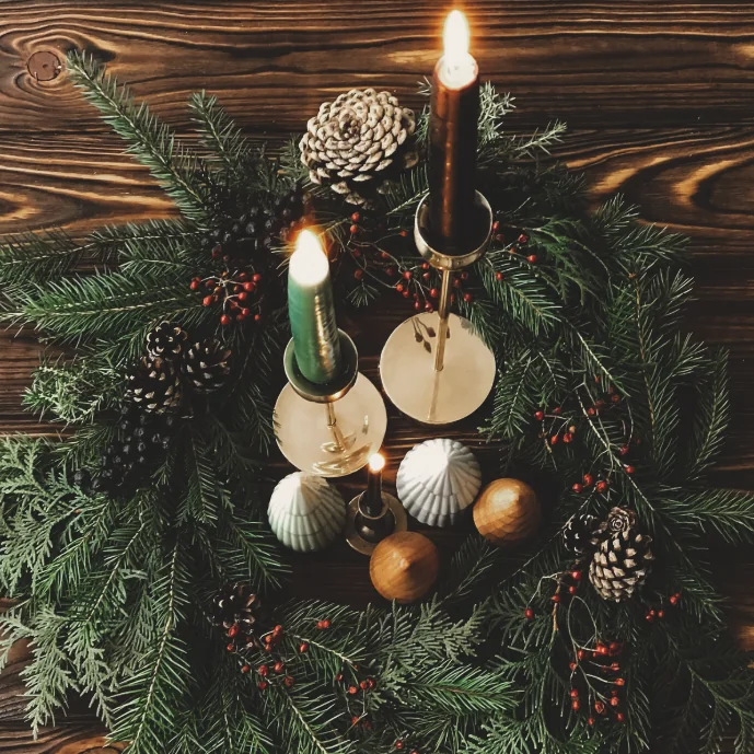 A Christmas table wreath of spruce, cones and berries with candles set into the centre